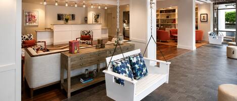 A modern interior with a hanging swing chair, a wooden console table, and a hexagonal tiled floor.