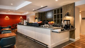 Eine moderne Hotelhalle mit einer zentralen Rezeption, einer Sitzecke und einem Fernsehbildschirm.