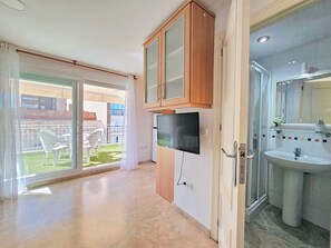 Eine moderne Küche mit Holzschränken, einem eingebauten Fernseher und einem Badezimmer mit Waschbecken und Spiegel.