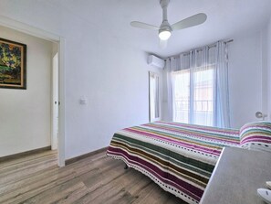 A bedroom with a bed, a ceiling fan, a window with curtains, and a door. - Sweet Home Cabo de Palos by Interhome (Cabo de Palos)
