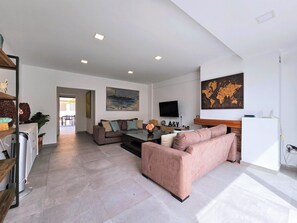 A modern living room with a sofa, coffee table, and a TV. There is a world map on the wall and a painting above the sofa. - Sweet Home Cabo de Palos by Interhome (Cabo de Palos)