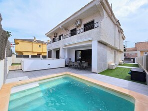 Une maison à deux étages avec une piscine, un espace salon extérieur et une pelouse bien entretenue.