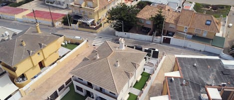 An aerial view of a coastal residential area with houses, a swimming pool, and a beach.