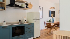 A modern kitchen with teal cabinets, a black oven, a white refrigerator, and a dining area with a wooden table and chairs. - 2-bedroom apartment with lakeview in beautiful Brenzone sul Garda with AC (Brenzone sul Garda)
