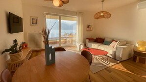 A modern living room with a dining table, sofa, and a view of the sea. - 2-bedroom apartment with lakeview in beautiful Brenzone sul Garda with AC (Brenzone sul Garda)