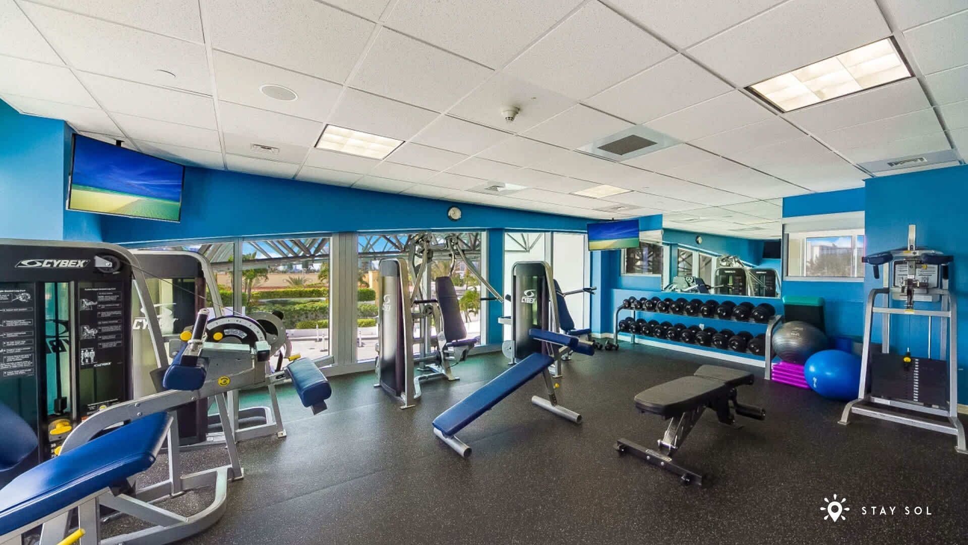 Een sportschool met diverse fitnessapparaten, waaronder krachttrainingsmachines en gewichten.