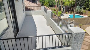 Ein Balkon mit Metallgeländer, ein Pool und eine kleine Terrasse mit Gartenmöbeln.