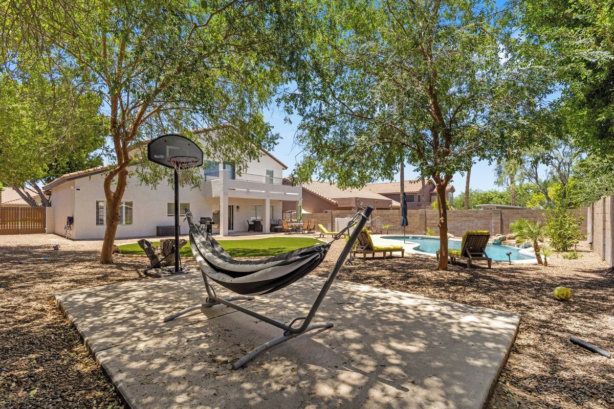 Uma rede em um quintal com piscina e uma casa ao fundo.