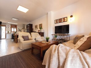 Ein Wohnzimmer mit einer Couch, einem Couchtisch, einem Fernseher und einem Essbereich mit Stühlen und einem Tisch.