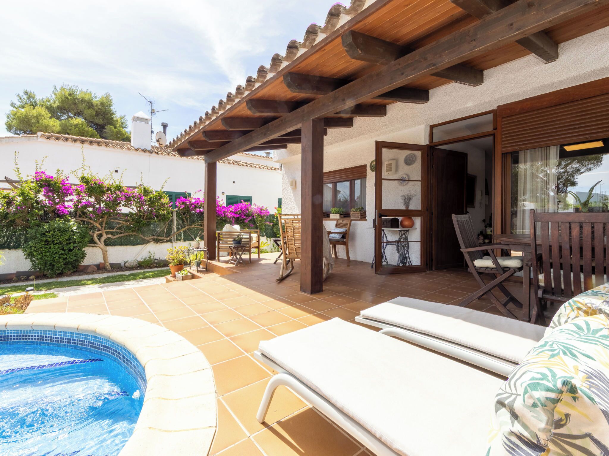 A poolside area with a pergola, lounge chairs, and a small table with chairs.