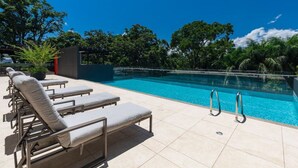 Ein Poolbereich mit Liegestühlen und umliegender Bepflanzung.