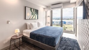 Ein modernes Hotelzimmer mit einem großen Bett, Blick auf das Flughafengelände und einer Klimaanlage.