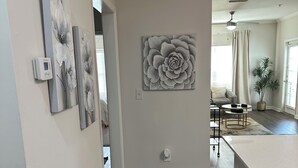 Ein Flur mit einem grauen Streifen Teppich, einem schwarzen Mülleimer und einer Wanddekoration mit grauem Blumenmuster.