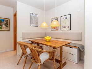 A dining area with a wooden table, wicker chairs, and a bench. - Vacation home Claudi by Interhome (Tossa de Mar)