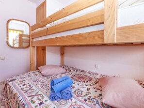 A bunk bed with a wooden frame, a patterned bedspread, and rolled towels. - Vacation home Claudi by Interhome (Tossa de Mar)