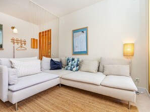 A modern living room with a sectional sofa, a woven rug, a wall-mounted lamp, and a framed picture. - Vacation home Claudi by Interhome (Tossa de Mar)