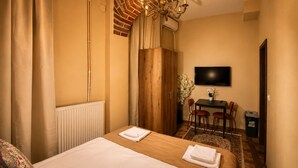Une chambre d’hôtel avec un lit, un bureau avec des chaises, une télévision et un lustre.