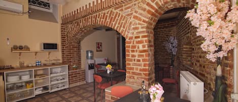 Un coin repas agrémenté d’arches en briques, d’une table avec des chaises et d’un vase rempli de fleurs.
