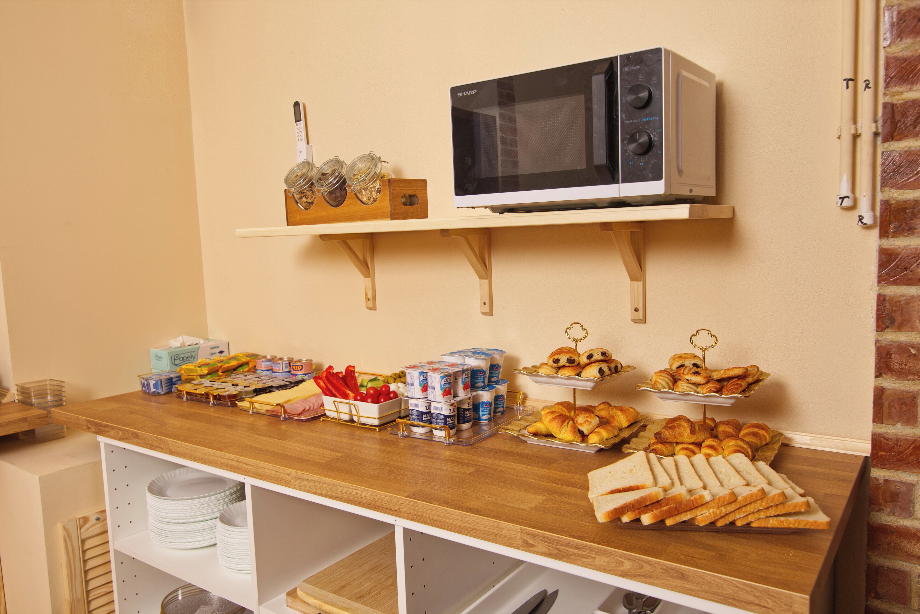 A buffet setup with a microwave, various food items, and condiments.