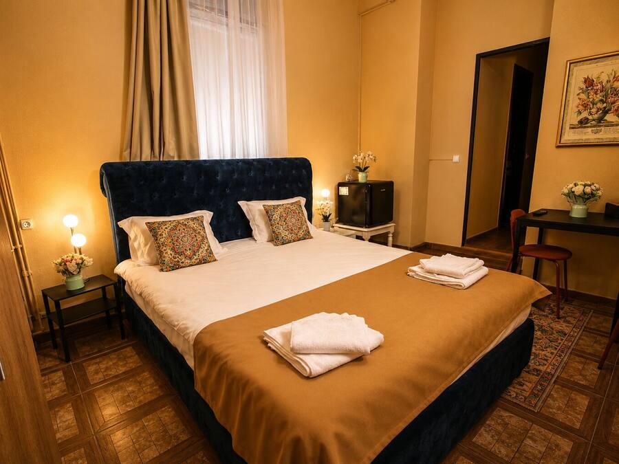 Una habitación de hotel con cama, mesitas de noche, escritorio y una silla.