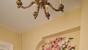 Un salon avec un canapé gris, un radiateur, une plante en pot et une composition florale murale.