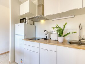 Eine moderne Küche mit weißen Schränken, einem eingebauten Ofen, einem Toaster und einer Topfpflanze.