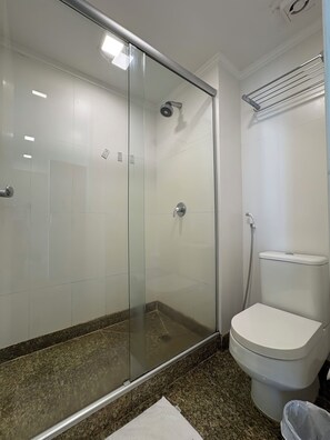 Un baño con ducha de vidrio, inodoro y encimera de granito.