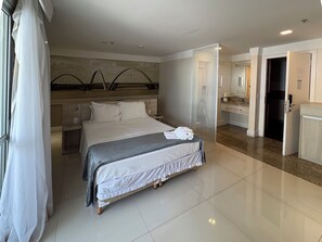 Una habitación de hotel con cama, baño y una zona de cocina.