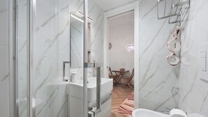 Uma casa de banho moderna com cabine de duche em vidro, lavatório branco e sanita.