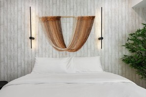 Ein Bett mit weißer Bettwäsche, eine Wand aus vertikalen Holzbrettern und zwei Wandlampen.