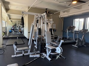 A gym with exercise equipment, treadmills, and a ceiling fan.