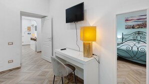A hotel room with a desk, chair, TV, lamp, and a bed with a metal frame. - Apartment 'A casa re nonni' with Balcony, Wi-Fi and Air Conditioning (Naples)