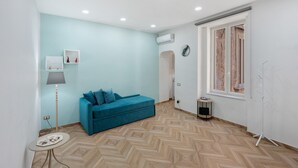 A room with a blue sofa, a standing lamp, a small table, and a herringbone-patterned floor. - Apartment 'A casa re nonni' with Balcony, Wi-Fi and Air Conditioning (Naples)