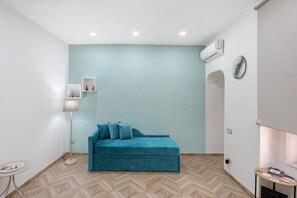 A room with a teal-colored sofa, a small table, a floor lamp, and a clock on the wall. - Apartment 'A casa re nonni' with Balcony, Wi-Fi and Air Conditioning (Naples)