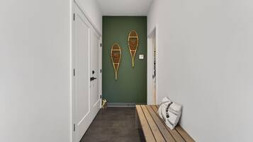 Un pasillo con un banco, dos adornos en la pared y una puerta.