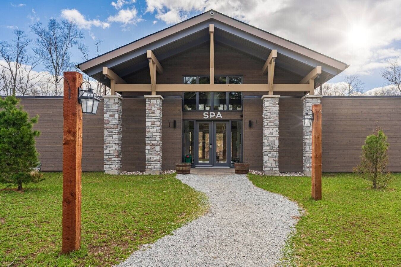 Un edificio de spa con fachada de piedra, un acceso cubierto y un camino de grava que lleva a la entrada.