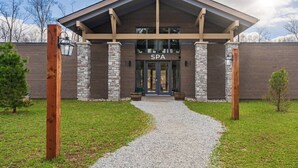 Un bâtiment abritant un centre de bien-être, doté d’une façade en pierre, d’une entrée couverte et d’un chemin de gravier menant à l’entrée.