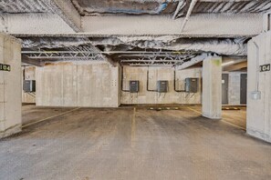 Un estacionamiento con paredes de concreto, rejillas de ventilación metálicas y espacios numerados.