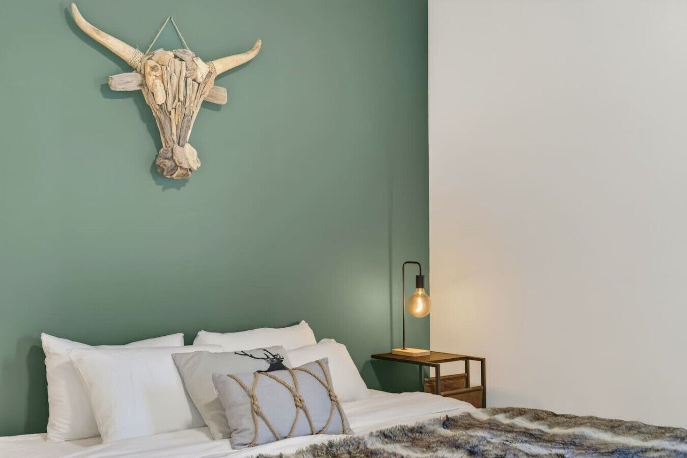 Un dormitorio con cama, almohadas, una lámpara de pared y un adorno mural.