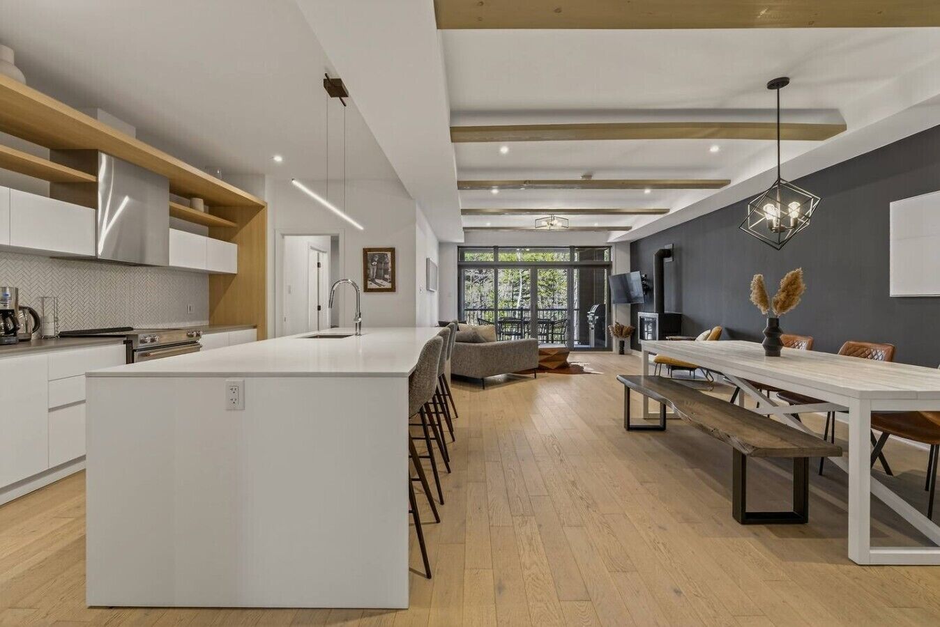 A modern kitchen with a central island, a dining area with a long table, and a seating arrangement.