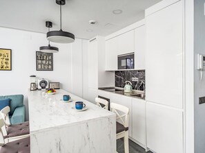 A modern kitchen with white cabinets, a marble island, a black and white backsplash, and a kettle on the counter. - Abedules by Interhome (Benalmádena Costa)