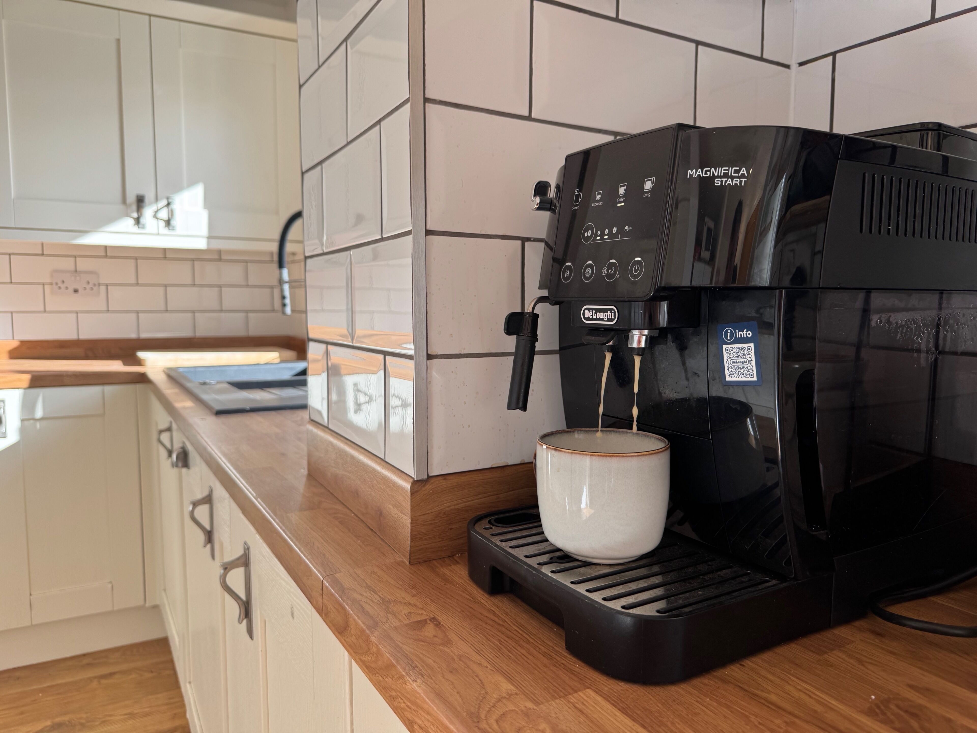 A coffee machine with a cup on its drip tray, a QR code, and a control panel with various buttons.