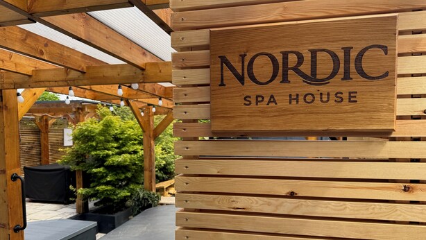 Une pergola en bois sur laquelle est apposée une enseigne indiquant : « NORDIC SPA HOUSE ».