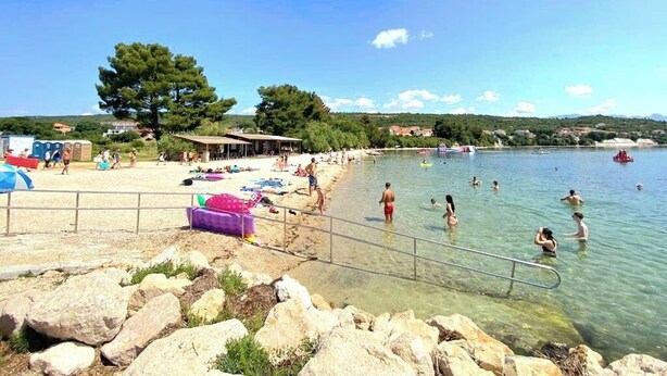 A beach with clear water, rocks, and a few people swimming. - Olive Garden -Family Villa with Private Pool in Posedarje near Zadar (Posedarje)
