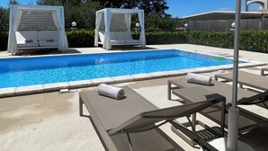 A swimming pool with lounge chairs and umbrellas, surrounded by greenery and a clear sky. - Olive Garden -Family Villa with Private Pool in Posedarje near Zadar (Posedarje)