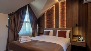A hotel room with a large bed, a bedside telephone, and a brick-patterned wall. - Hotel Chateau Cojusna (Cojușna)