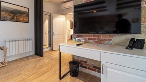 A modern room with a TV, desk, and a brick wall. - Hotel Chateau Cojusna (Cojușna)