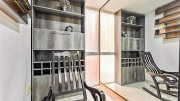 Una habitación con estanterías de madera, un sillón mecedora y una puerta que da a otra estancia.