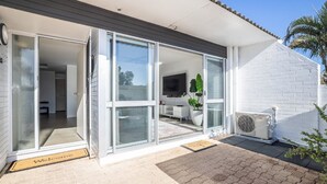 Ett modernt hus med en entré bestående av en skjutdörr i glas, ett platt tak och en vit tegelstensfasad.
