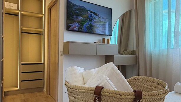 Hotellihuone, jossa on sänky, seinälle asennettu televisio, vaatekaappi ja punottu kori, jonka kylkeen on kirjoitettu teksti »Cabo Negro».
